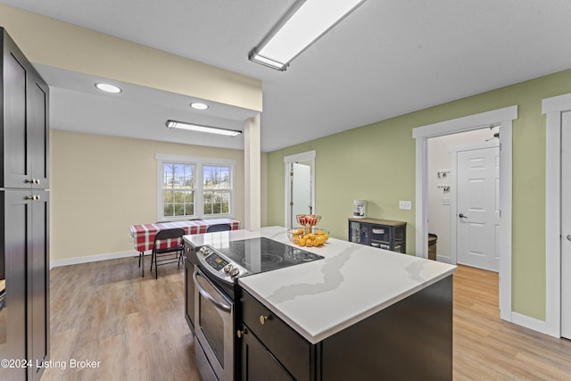 kitchen featuring stainless steel electric range oven, a center island, light hardwood / wood-style floors, and light stone counters