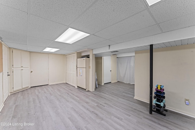 basement with a paneled ceiling, white fridge, and light hardwood / wood-style floors