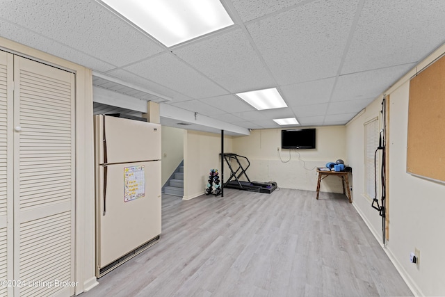 exercise room with a drop ceiling and light hardwood / wood-style floors