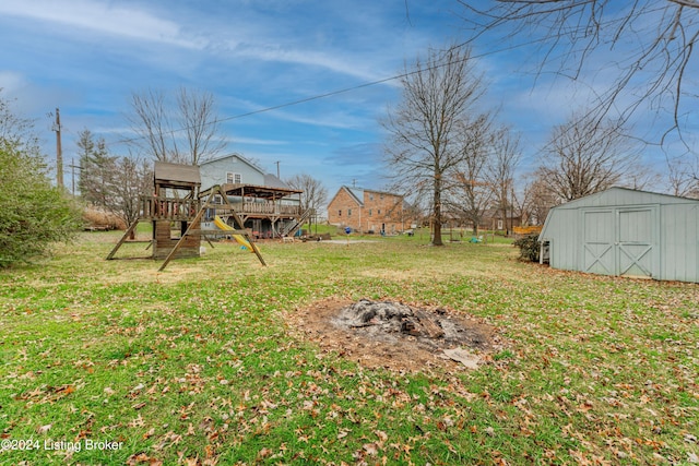 view of yard featuring a playground, a shed, a deck, and an outdoor fire pit