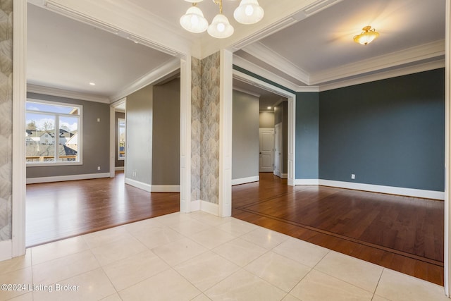 unfurnished room with light wood-type flooring, ornamental molding, and a notable chandelier