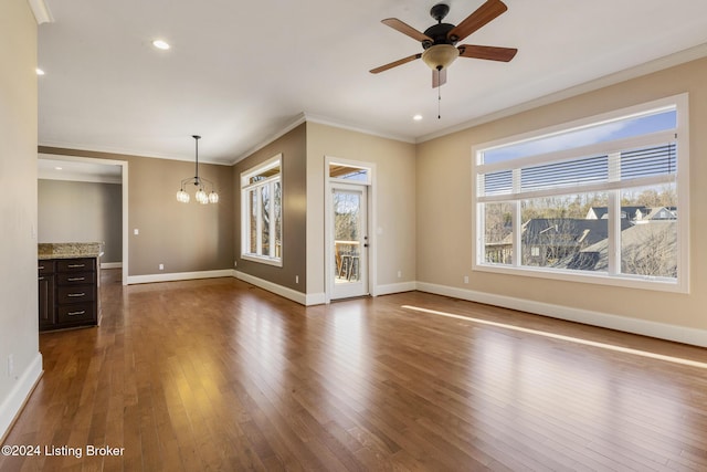 unfurnished living room with ceiling fan with notable chandelier, dark hardwood / wood-style floors, and ornamental molding