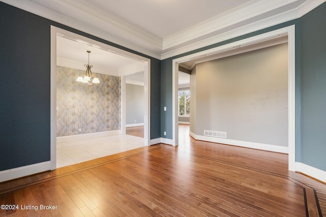 spare room with hardwood / wood-style flooring, a notable chandelier, and ornamental molding