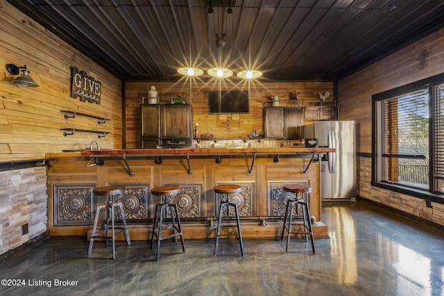 bar with stainless steel fridge, wooden ceiling, and wooden walls