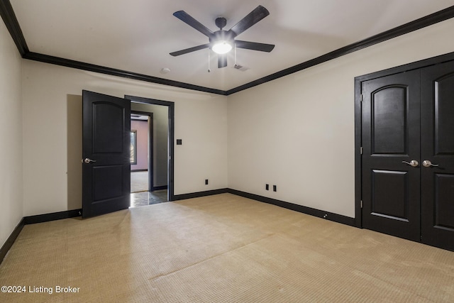 unfurnished bedroom with ceiling fan, light colored carpet, and crown molding