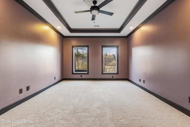 carpeted spare room featuring a tray ceiling, crown molding, and ceiling fan