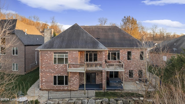 back of house with a balcony, a patio area, and a lawn