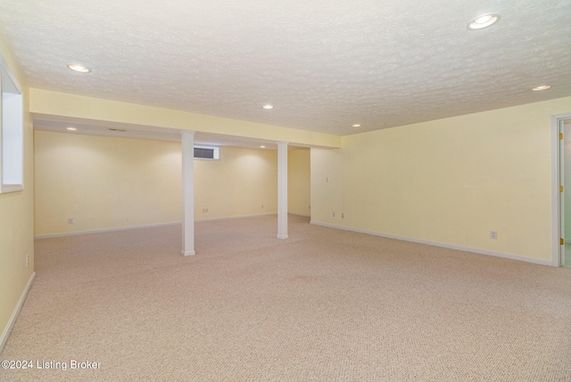 basement featuring a textured ceiling and light colored carpet