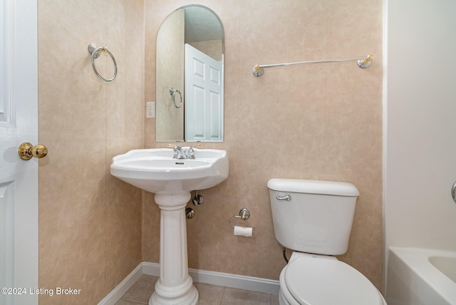 bathroom featuring tile patterned flooring, toilet, and a tub