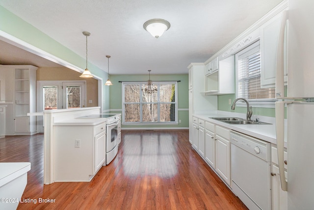 kitchen featuring pendant lighting, white appliances, sink, white cabinetry, and a chandelier