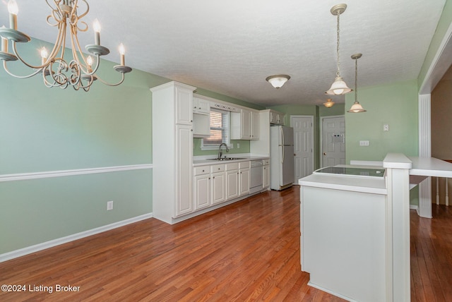 kitchen with pendant lighting, white appliances, white cabinets, hardwood / wood-style flooring, and a textured ceiling