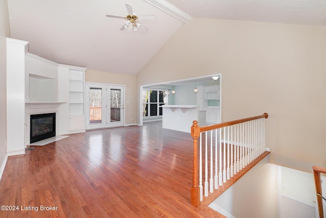 unfurnished living room with hardwood / wood-style flooring, ceiling fan, beam ceiling, and high vaulted ceiling