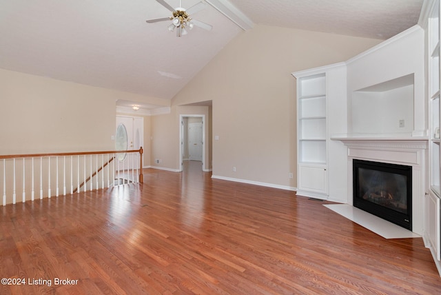 unfurnished living room featuring built in shelves, vaulted ceiling with beams, hardwood / wood-style flooring, and ceiling fan