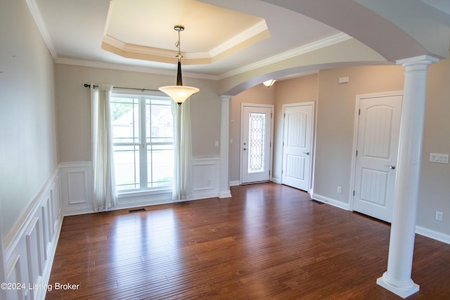 entryway featuring a raised ceiling, crown molding, dark wood-type flooring, and decorative columns