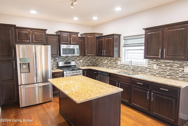 kitchen with a kitchen island, sink, light wood-type flooring, and stainless steel appliances