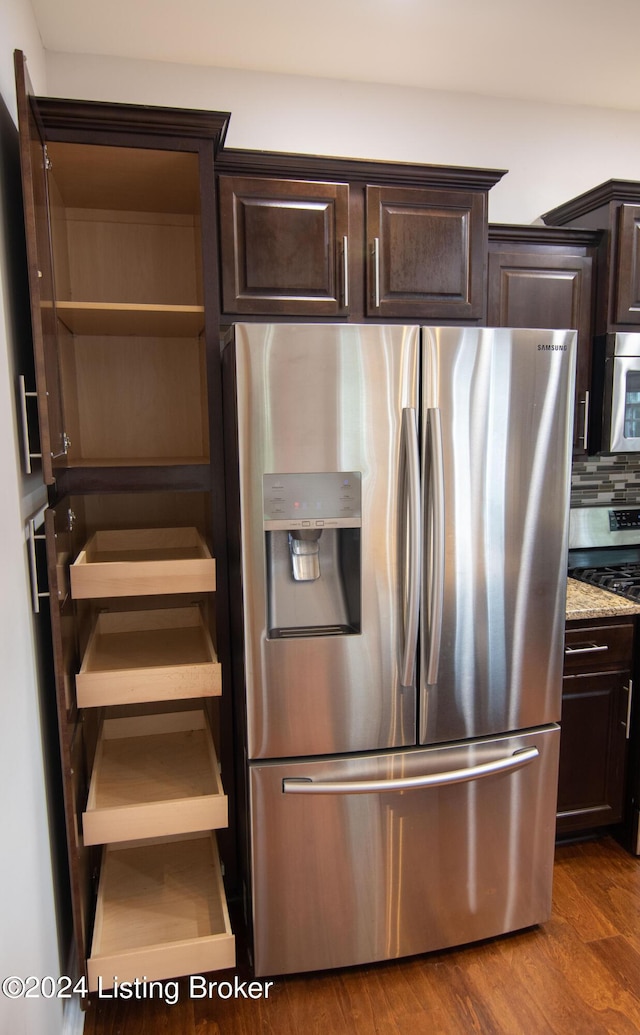 kitchen featuring dark wood-type flooring, light stone countertops, tasteful backsplash, dark brown cabinets, and stainless steel appliances