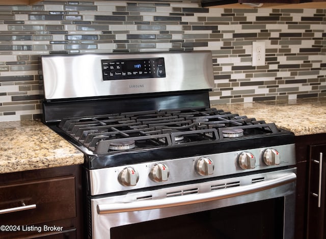 kitchen with light stone countertops, dark brown cabinets, backsplash, and stainless steel gas range oven