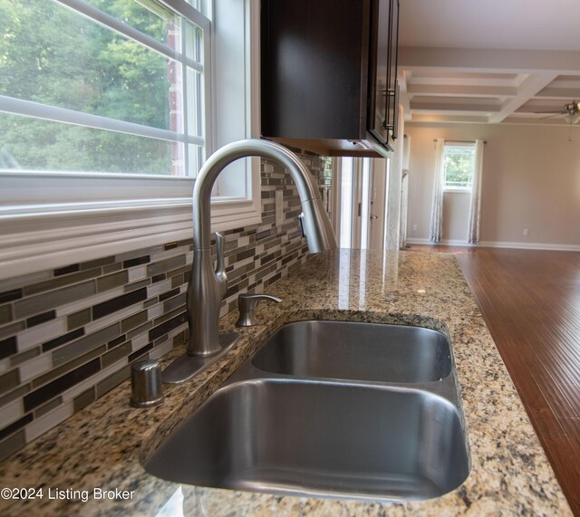 details featuring beam ceiling, stone counters, sink, coffered ceiling, and tasteful backsplash