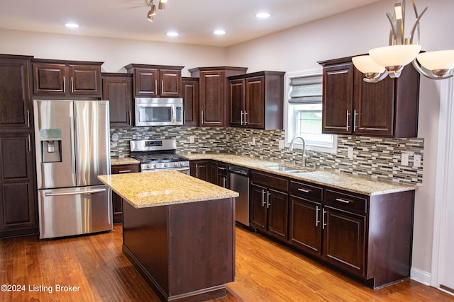 kitchen featuring sink, a center island, backsplash, hardwood / wood-style floors, and appliances with stainless steel finishes