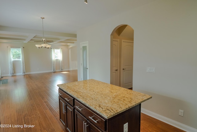 kitchen featuring coffered ceiling, hardwood / wood-style flooring, an inviting chandelier, beamed ceiling, and a kitchen island