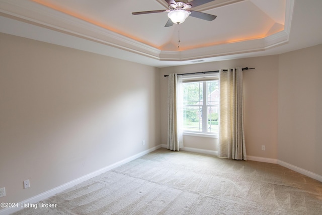 carpeted spare room with a tray ceiling, ceiling fan, and crown molding