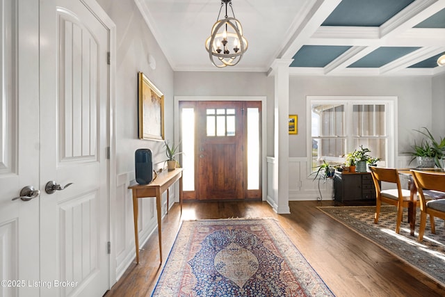 entrance foyer featuring an inviting chandelier, beamed ceiling, ornamental molding, coffered ceiling, and dark hardwood / wood-style flooring