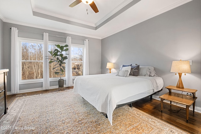 bedroom featuring crown molding, hardwood / wood-style flooring, ceiling fan, and a tray ceiling