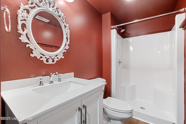 bathroom featuring toilet, walk in shower, and vanity