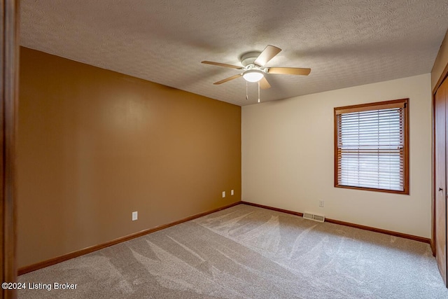 carpeted spare room featuring a textured ceiling and ceiling fan