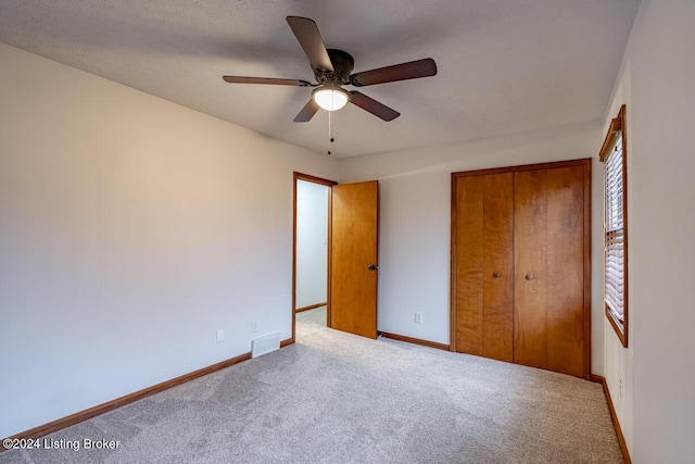 unfurnished bedroom with light colored carpet, ceiling fan, and a closet