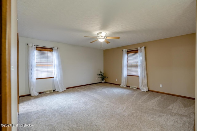 unfurnished room featuring ceiling fan, light carpet, and a textured ceiling