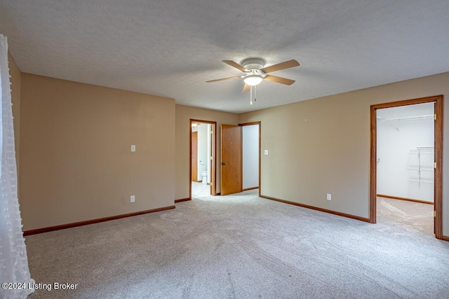 empty room featuring ceiling fan, light carpet, and a textured ceiling