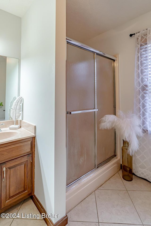 bathroom with tile patterned floors, a shower with shower door, and vanity