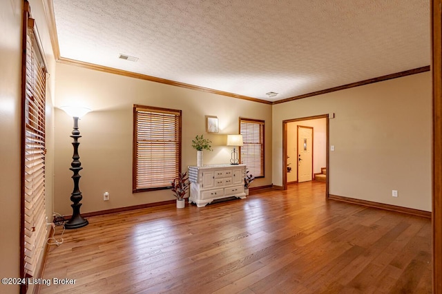 unfurnished room with ornamental molding, light hardwood / wood-style flooring, and a textured ceiling