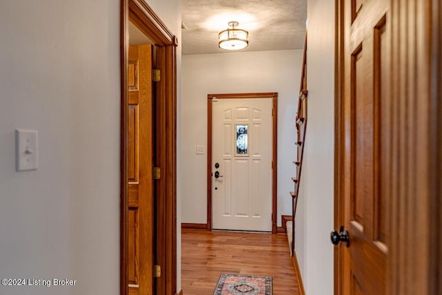 doorway to outside featuring light hardwood / wood-style flooring and a textured ceiling