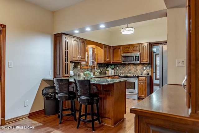 kitchen featuring tasteful backsplash, stainless steel appliances, a breakfast bar, and kitchen peninsula