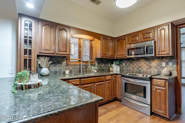 kitchen with sink, decorative backsplash, stainless steel appliances, and light wood-type flooring