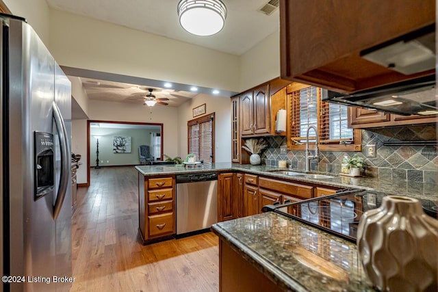 kitchen featuring appliances with stainless steel finishes, sink, backsplash, light hardwood / wood-style floors, and kitchen peninsula