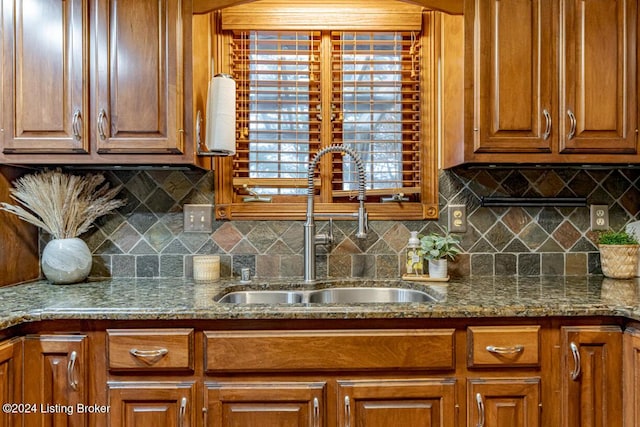 kitchen featuring dark stone countertops, sink, and backsplash