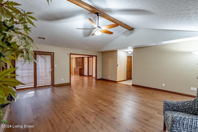 unfurnished living room featuring hardwood / wood-style flooring, ceiling fan, lofted ceiling with beams, and a textured ceiling