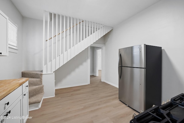 kitchen with white cabinetry, wood counters, stainless steel fridge, and light wood-type flooring