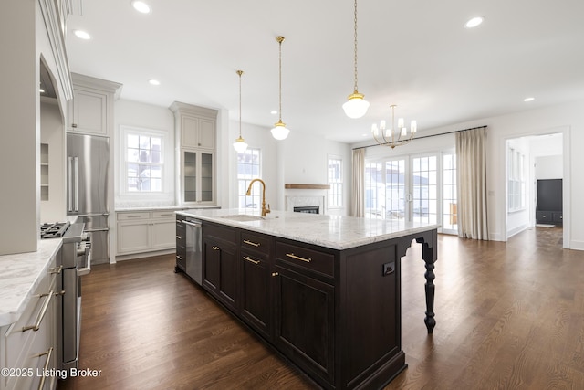 kitchen with premium appliances, light stone counters, pendant lighting, a kitchen bar, and a center island with sink