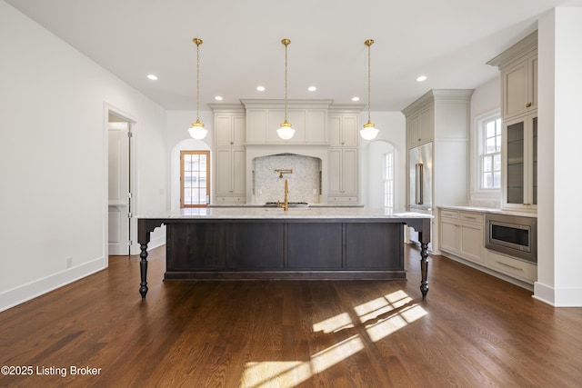 kitchen with built in appliances, dark hardwood / wood-style flooring, a spacious island, and hanging light fixtures