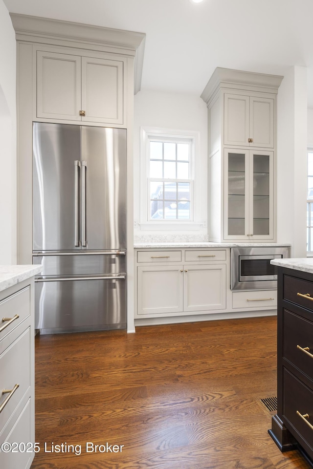 kitchen featuring light stone countertops, dark wood-type flooring, and appliances with stainless steel finishes