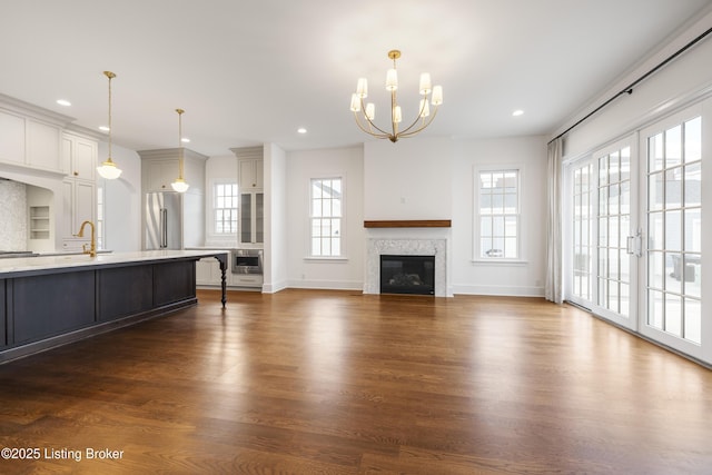 unfurnished living room with dark hardwood / wood-style floors, french doors, a wealth of natural light, and a chandelier