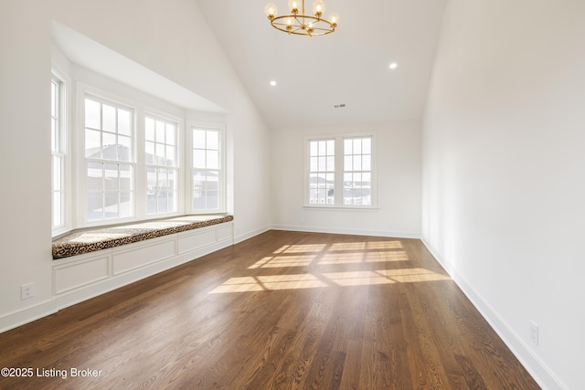 empty room featuring dark hardwood / wood-style flooring, high vaulted ceiling, and a notable chandelier