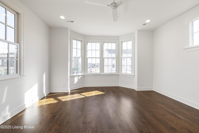 spare room featuring a wealth of natural light, dark wood-type flooring, and ceiling fan