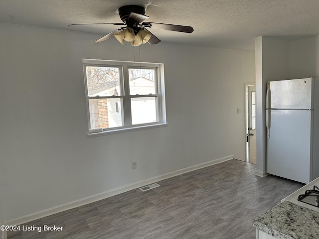 kitchen featuring ceiling fan, white fridge, and a textured ceiling