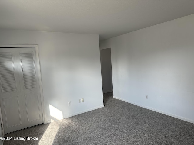 unfurnished bedroom featuring dark carpet and a closet