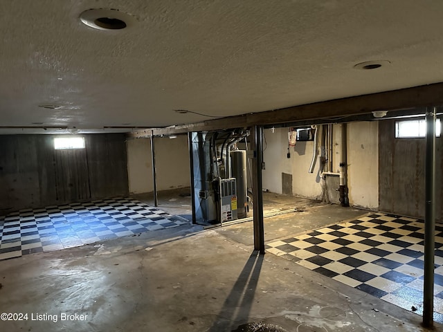 basement with heating unit, a textured ceiling, and water heater